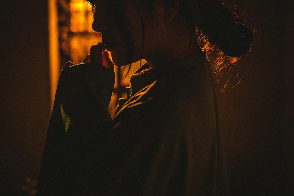 A woman in warm, low light with a hand raised near her face.