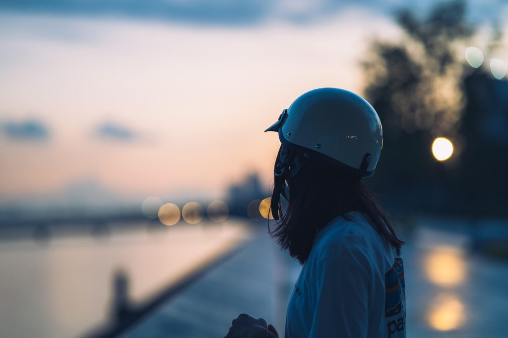 A person wearing a helmet looking out over water at dusk.