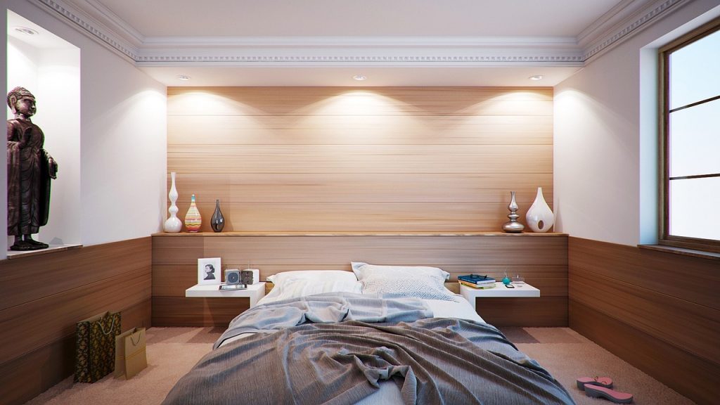 A neatly made bed in a warmly lit modern bedroom.