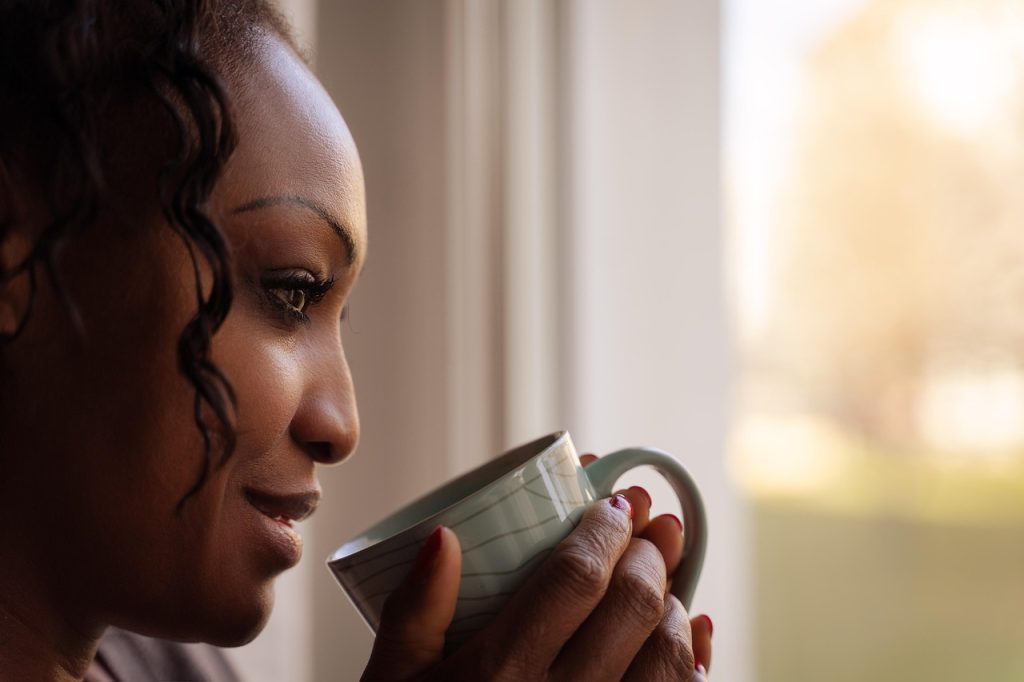 Woman holding a mug and looking out of a window.