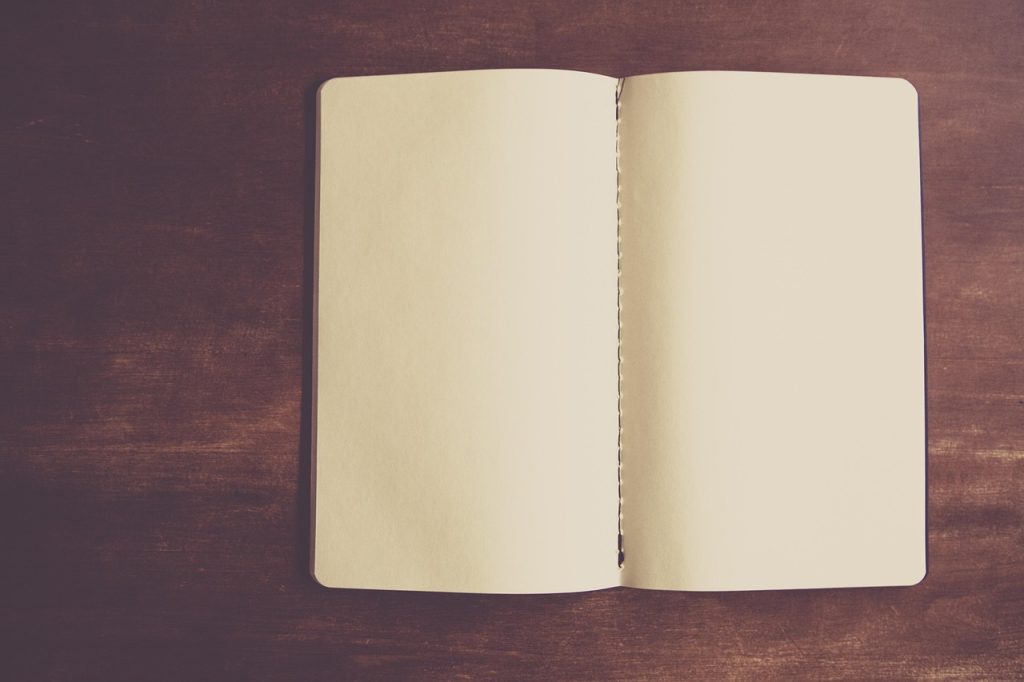 An open blank notebook resting on a dark wooden table.