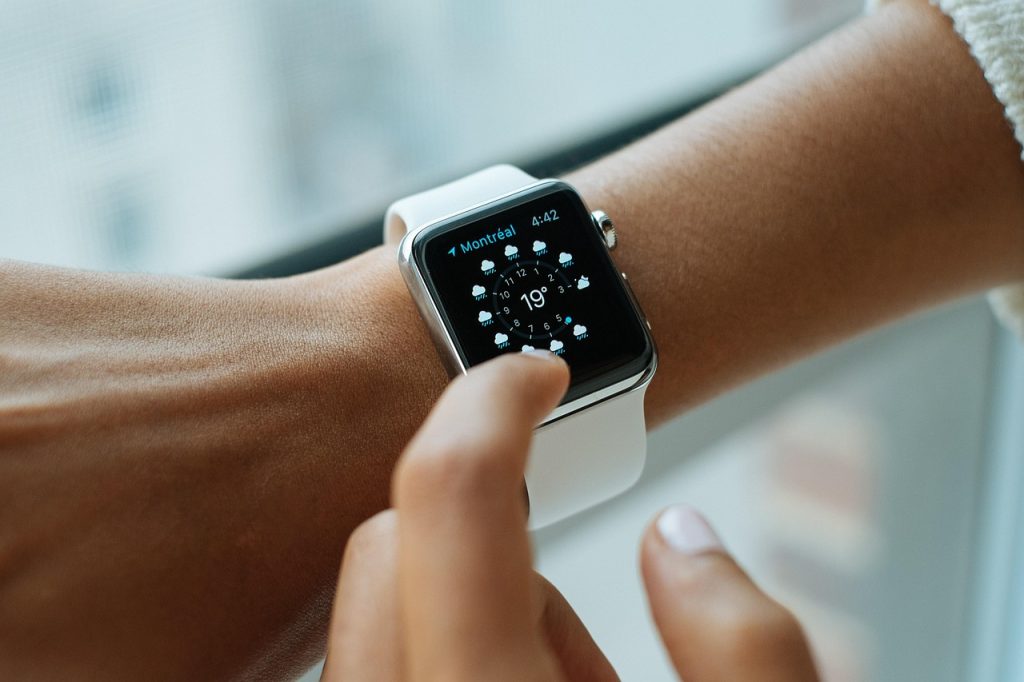 A close-up of a smartwatch on a wrist, with a fingertip touching the screen.